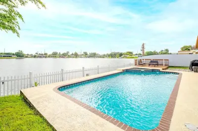 a swimming pool next to a body of water at Stunning Lake-Front Villa with Pool & Spa in Pembroke Pines
