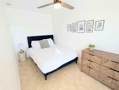 a bedroom with a white bed and a wooden dresser at Stunning Lake-Front Villa with Pool & Spa in Pembroke Pines