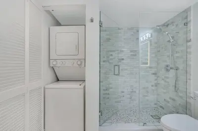 a white bathroom with a shower and a toilet at Deluxe 1 BR suite with Pool, Parking, Balcony and Ocean Views in Miami