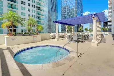 a hot tub in a patio with tables and chairs at Deluxe 1 BR suite with Pool, Parking, Balcony and Ocean Views in Miami