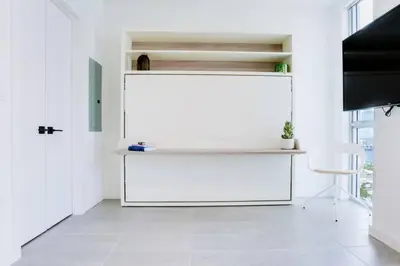 a white room with a white desk and a chair at Modern and newly built studio with Pool, Gym, and Restaurant access in Miami