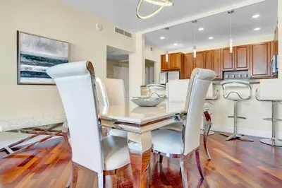 a dining room with a table and white chairs at Lux 2BR Condo in Ocean Reserve with Pools and Tennis Courts in Miami Beach
