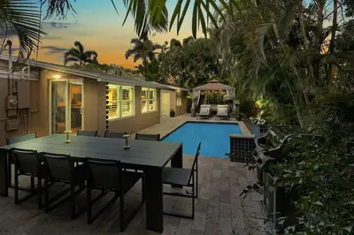 a house with a table and chairs next to a pool at Modern 2BRHouse in Wilton Manors with a Heated Pool and KING Bed in Fort Lauderdale