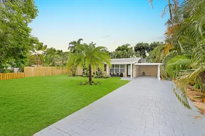 a house with a green yard with a driveway at Modern 2BRHouse in Wilton Manors with a Heated Pool and KING Bed in Fort Lauderdale