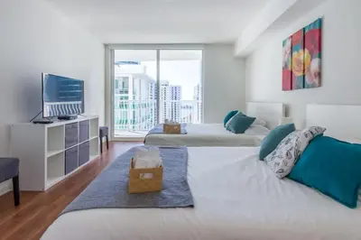 a bedroom with two beds and a tv and a large window at Ocean and City Views Lux Miami Brickell Sleeps 5 in Miami