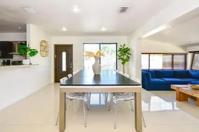 a dining room with a table and a blue couch at Five Bedroom Villa With POOL In Highland Lakes Near Aventura Mall in Miami