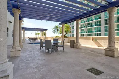 a patio with a table and chairs and a building at 3BR Airbnb Friendly Condo with Ocean View and Balcony in Miami