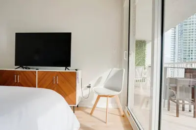 a bedroom with a bed and a tv and a chair at Ocean and City Views Lux Miami Brickell Condo Sleeps 4, King Bed in Miami