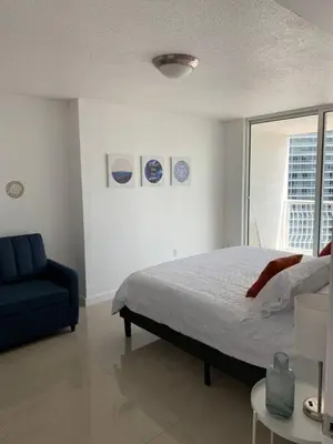 a bedroom with a bed and a blue chair at Sunshine Ocean and City Views 1 BR Paradise with Parking in Miami
