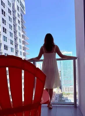 a woman in a white dress standing on a balcony at Sky-High oasis heated Pool & Gym Miami Skyline Vista in Miami