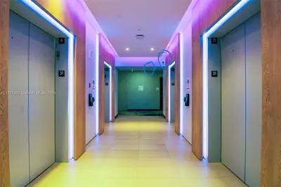 a hallway with pink and green walls and a long corridor at Sky-High oasis heated Pool & Gym Miami Skyline Vista in Miami