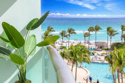 a view of the beach from the balcony of a resort at Beachfront 1-Bedroom Apartment with Ocean View, Pool and Gym in Hollywood Beach in Hollywood