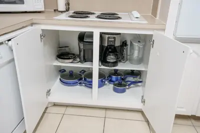 a kitchen cupboard with a stove and dishes in it at Beachfront 1-Bedroom Apartment with Ocean View, Pool and Gym in Hollywood Beach in Hollywood