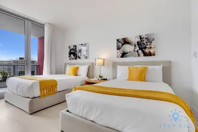 two beds in a room with a window at Infinite View Balcony with Pool, Gym and Near Beach in Hallandale Beach