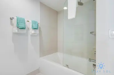 a bathroom with a tub and a shower with blue towels at Infinite View Balcony with Gym, Pool and Near Beach in Hallandale Beach