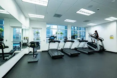 a gym with cardio equipment and a woman on a treadmill at City views at brickell miami in Miami