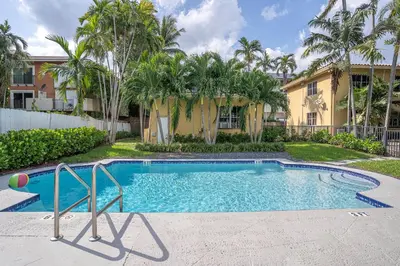 a swimming pool in front of a house with palm trees at Oia House Brickell Beach 10 minutes Pool Location in Miami