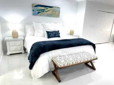 a white bedroom with a bed with a blue blanket at Home in Miami in Miami
