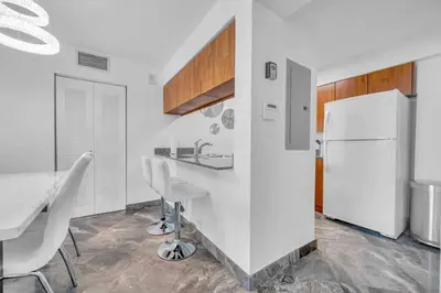 a white kitchen with a table and a refrigerator at Iconic High floor 3 bedrooms in the heart of Miami in Miami