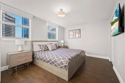 a bedroom with a bed and a nightstand and two windows at Ocean view 35th floor, in the heart of Miami in Miami