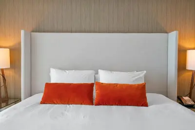 a white bed with two orange pillows on it at 15th-Floor Luxury 1BR at Lyfe Resort with Ocean View in Hollywood