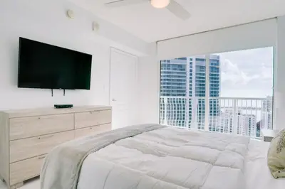 a white bedroom with a large bed and a large window at 2BR Penthouse with Unbeatable Water Views and Parking in Miami
