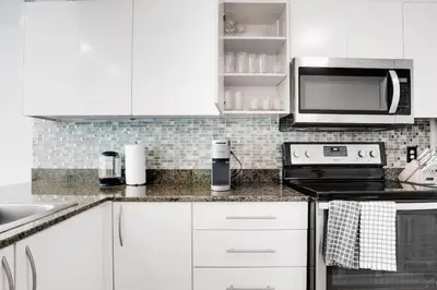 a kitchen with white cabinets and a microwave at 2BR Penthouse with Unbeatable Water Views and Parking in Miami
