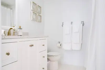a white bathroom with a toilet and a sink at 2BR Penthouse with Unbeatable Water Views and Parking in Miami