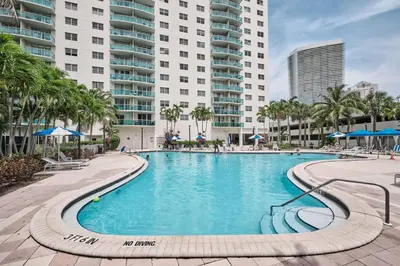 a large swimming pool with palm trees and buildings at MIAMI Collins Beach Apartments in Sunny Isles Beach