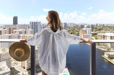 a woman standing on a balcony looking out at the city at High Floor with Stunning Views Amazing Pools in Hollywood