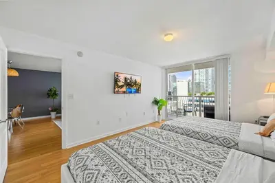 a white bedroom with two beds and a balcony at Amazing cozy Condo in Brickell Miami in Miami