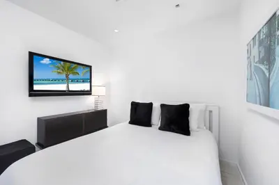a bedroom with a white bed with a tv on the wall at Oceanfront Private Residence at South Beach - 828 in Miami Beach