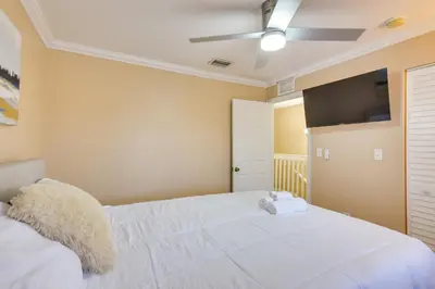a bedroom with a white bed and a flat screen tv at Opa-locka Townhome, 15 Mi to Miami Beach! in Opa-locka