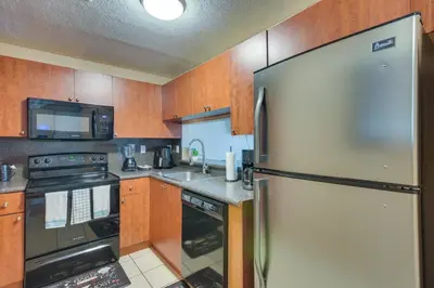 a kitchen with a stainless steel refrigerator and a microwave at Opa-locka Townhome, 15 Mi to Miami Beach! in Opa-locka