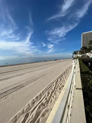 a sandy beach with a white fence and palm trees at Miami Hollywood Gorgeous 2BD Awesome Ocean View in Hollywood