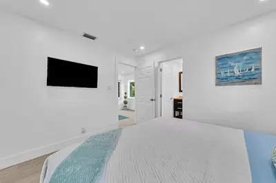a white bedroom with a bed and a flat screen tv at Quiet and secluded 4 bedroom home! in Fort Lauderdale