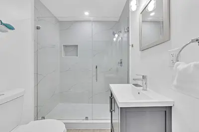 a white bathroom with a shower and a sink at Quiet and secluded 4 bedroom home! in Fort Lauderdale