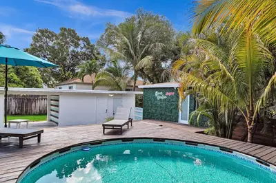 a swimming pool on a wooden deck next to a house at Quiet and secluded 4 bedroom home! in Fort Lauderdale