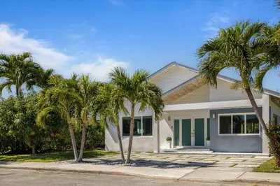 a white house with palm trees in front of it at Luxury House 4 beds heated Pool w Jaccuzzi in North Bay Village
