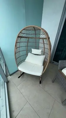 a rattan chair with pillows sitting on a balcony at Beachfront Condo with Mesmerizing Views in Hollywood