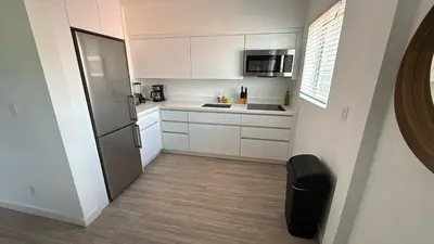 a small kitchen with white cabinets and a refrigerator at Beautiful Apt 2/2 Near The Beach in Miami