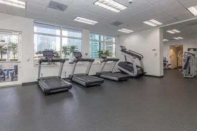 a gym with treadles and ellipticals in a room with windows at Warm and Tailored 1BR w Pool Hot tub GYM Parking in Miami