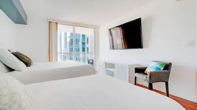 a bedroom with two beds and a chair and a window at Warm and Tailored 1BR w Pool Hot tub GYM Parking in Miami