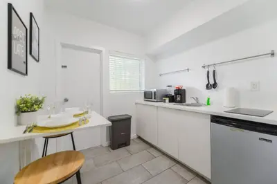 a white kitchen with a table and a counter top at Great Studio Residence 15 min from the beach in Miami