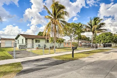 a house on a street with a fence and palm trees at Gated Southern Miami Home 22 Mi to Downtown! in Miami