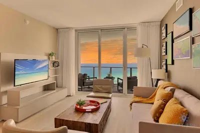 a living room with a couch and a television at Ocean View Balcony Beachfront Resort Amazing Pools in Hollywood