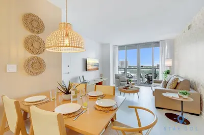 a dining room and living room with a table and chairs at Pool - Apartment with Balcony - Gym - Near Beach in Hallandale Beach