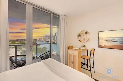 a bedroom with a bed and a desk and a balcony at Pool - Apartment with Balcony - Gym - Near Beach in Hallandale Beach