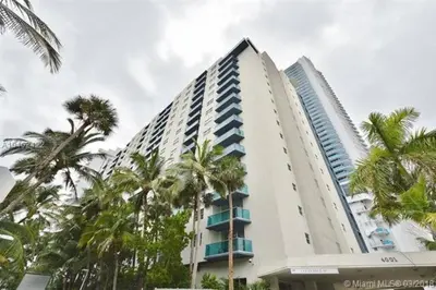 a tall white building with palm trees in front of it at Beautiful penthouse condo with stunning views of both ocean and city in Hollywood