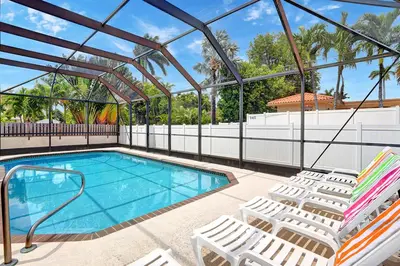 a swimming pool with white chairs and a swimming poolvisor at Deluxe 5BR Villa Heated Pool near Hollywood Beach in Hollywood